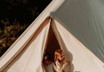 Due bambini in pigiama escono dalla Bell Tent 500 presso REBL Outdoor nei Paesi Bassi con peluche.
