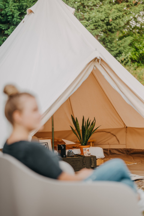 Foto de la tienda safari Bell Tent 500 en REBL Outdoor, Países Bajos, con una persona en primer plano.