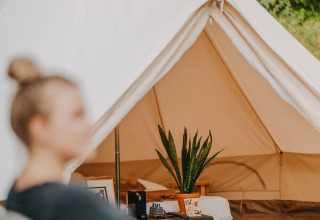 Photo de la tente safari Bell Tent 500 chez REBL Outdoor aux Pays-Bas, avec une personne au premier plan.