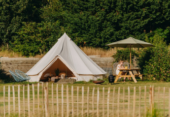 Safari-Zelt Bell Tent 500 bei REBL Outdoor in den Niederlanden, neben Picknicktisch und grünem Gelände.