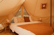 Indretning af soveområdet i Bell Tent Emperor ved REBL Outdoor, Nederlandene, med rustikke detaljer.