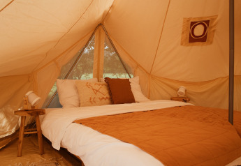 Habitación acogedora en la tienda Bell Tent Emperor de REBL Outdoor, Países Bajos, con tonos cálidos.