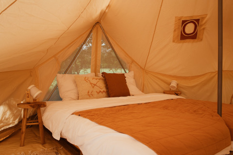 Indretning af soveområdet i Bell Tent Emperor ved REBL Outdoor, Nederlandene, med rustikke detaljer.