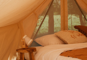 Intérieur de la tente Bell Tent Emperor chez REBL Outdoor aux Pays-Bas, avec lit confortable et déco bois.