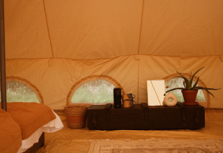 Interior de la tienda safari Bell Tent Emperor en REBL Outdoor, Países Bajos, con decoración acogedora.