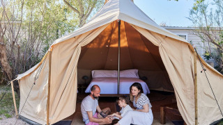 Famiglia si rilassa all'ingresso della Glamping Bell Tent Balsa al TAIGA Delta de l'Ebre in Spagna.
