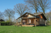 Safari-teltet Ranger Lodge i Recreation Park Den Blanken i Holland, omgivet af grønne træer og græs.