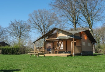 Safari-teltet Ranger Lodge i Recreation Park Den Blanken i Holland, omgivet af grønne træer og græs.