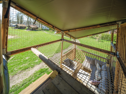 Uitzicht uit een safaritent Ranger Lodge in recreatiepark Den Blanken, Nederland, met net en zithoek.
