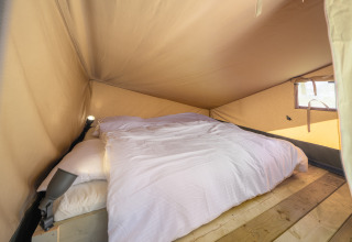 Interior de una tienda safari con cama en Ranger Lodge del Recreation Park Den Blanken, Países Bajos.