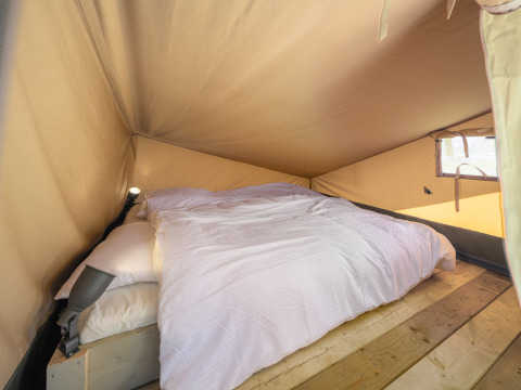 Interior de una tienda safari con cama en Ranger Lodge del Recreation Park Den Blanken, Países Bajos.