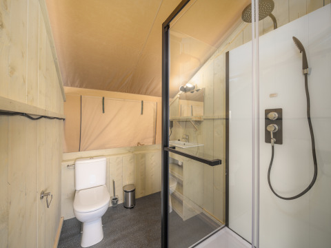 Badkamer in een Ranger Lodge safari tent bij Recreation Park Den Blanken, met douche en toiletvoorziening.