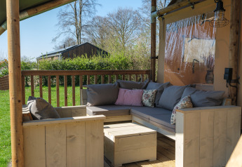 Buitenlounge met houten zetels en kussens op het terras van Ranger Lodge in Den Blanken, Nederland.