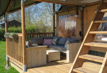 Cozy wooden terrace with seating furniture and stairs at the Ranger Lodge safari tent in the Netherlands.
