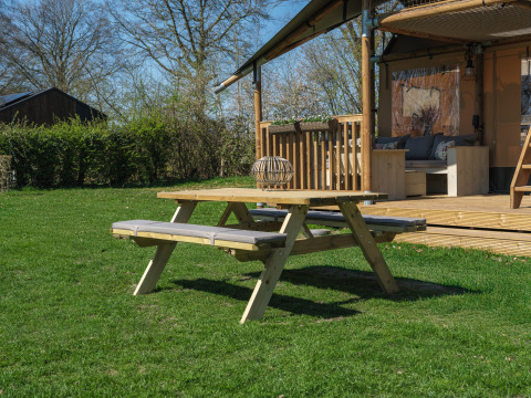 Picknicktisch auf einer Wiese vor dem Safari-Zelt Ranger Lodge im Erholungspark Den Blanken in den Niederlanden.