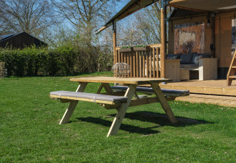 Picknicktisch auf einer Wiese vor dem Safari-Zelt Ranger Lodge im Erholungspark Den Blanken in den Niederlanden.