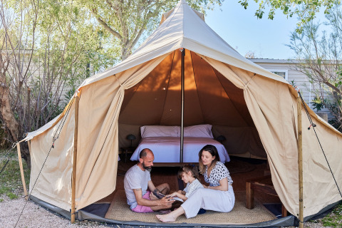 Familie vor einem Tipi-Zelt mit Bett innen am TAIGA Delta de l'Ebre, Spanien, beim Glamping.