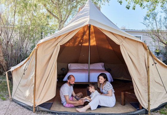 Famille assise devant une tente tipi avec lit à l'intérieur au TAIGA Delta de l'Ebre, Espagne.