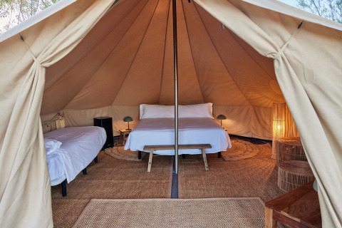 Vista interior de la Glamping Bell Tent Balsa con camas acogedoras y luz cálida en TAIGA Delta de l'Ebre, España.