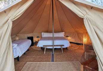 Vista interior de la Glamping Bell Tent Balsa con camas acogedoras y luz cálida en TAIGA Delta de l'Ebre, España.