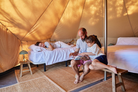 Familie entspannt und liest zusammen im Glamping Bell Tent Balsa bei TAIGA Delta de l'Ebre, Spanien.