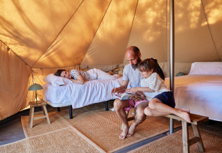 Familie entspannt und liest zusammen im Glamping Bell Tent Balsa bei TAIGA Delta de l'Ebre, Spanien.