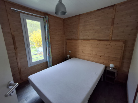 Gezellige slaapkamer in Chalet Pauline met houten lambrisering, tweepersoonsbed en groot raam.