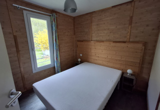 Gezellige slaapkamer in Chalet Pauline met houten lambrisering, tweepersoonsbed en groot raam.
