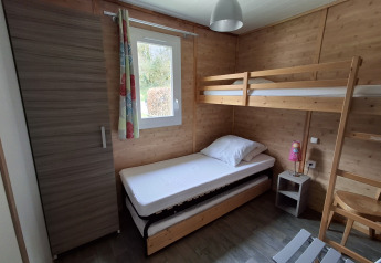 Et hyggeligt soveværelse i Chalet Pauline på Centre de Vacances Tariche, Schweiz, med køjeseng og skab.