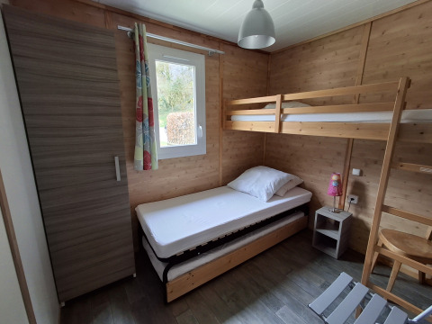 Et hyggeligt soveværelse i Chalet Pauline på Centre de Vacances Tariche, Schweiz, med køjeseng og skab.