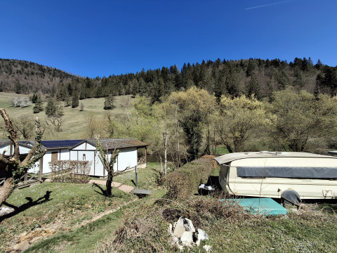 Zicht op Chalet Pauline aan Centre de Vacances Tariche in Zwitserland, met chalets, caravan en bos.