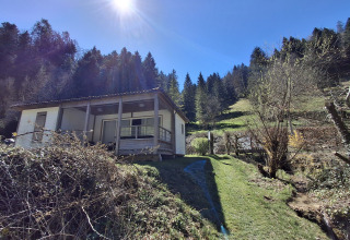 Chalet Pauline bij Centre de Vacances Tariche in Zwitserland, in de zon met bossen en groene heuvels.