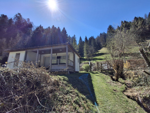 Chalet Pauline bij Centre de Vacances Tariche in Zwitserland, in de zon met bossen en groene heuvels.