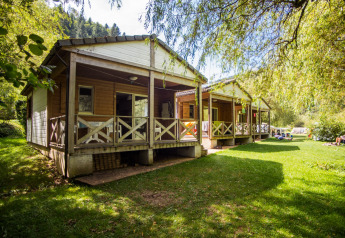 Træchalet kaldet Chalet confort med udsigt over floden, omgivet af grøn natur og afslappede gæster.