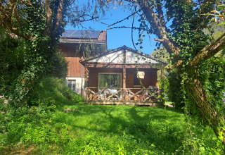 Chalet confort (vue rivière) au Centre de Vacances Tariche en Suisse, entouré de verdure luxuriante.