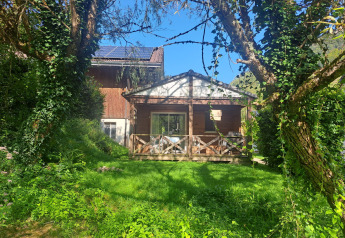 Chalet confort (vista al río) en Centre de Vacances Tariche, Suiza, rodeado de exuberante vegetación.