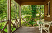 Træveranda med udsigt til flod og grøn skov ved Chalet confort, Centre de Vacances Tariche, Schweiz.