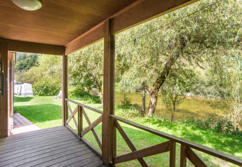 Blick von der Holzveranda des Chalet confort auf den Fluss im Centre de Vacances Tariche, Schweiz.