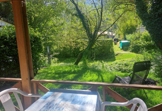 Udsigt fra en chalet på Centre de Vacances Tariche, Schweiz, med grøn have og omgivet af frodige træer.