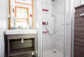 Modernes Badezimmer im Chalet Confort mit Dusche, Waschbecken und Spiegel im Centre de Vacances Tariche, Schweiz.