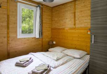 Soveværelse med trævægge og dobbeltseng i Chalet confort ved floden på Centre de Vacances Tariche.
