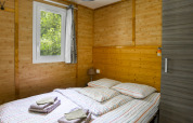 Schlafzimmer im Chalet confort am Centre de Vacances Tariche, Schweiz, mit Holzwänden und Doppelbett.