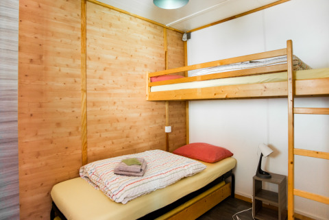 Gemütliches Zimmer mit Etagenbett und Einzelbett im Chalet confort im Centre de Vacances Tariche, Schweiz.