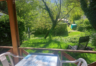 Udsigt over en frodig have og træer fra terrassen ved Chalet confort, Centre de Vacances Tariche, Schweiz.
