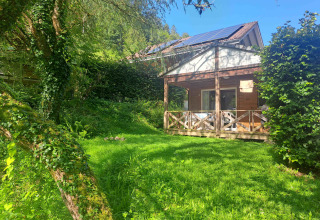 Hyggelig chalet med solpaneler, grøn græsplæne og terrasse ved Centre de Vacances Tariche i Schweiz.