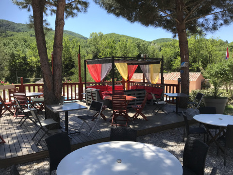 Espace extérieur à Flower Camping La Rivière avec tables et rideaux colorés au cœur de la Provence verte.