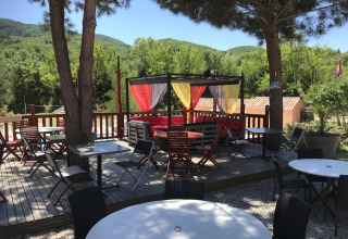Udendørs spiseområde i Flower Camping La Rivière, omgivet af grønne bakker i Provence-Alpes-Côte d’Azur.