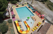 Luftfoto af swimmingpool med rutsjebane og liggestole på Flower Camping La Rivière i Provence, Frankrig.