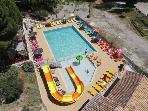 Luchtbeeld van zwembad met glijbaan en ligstoelen bij Flower Camping La Rivière in de Provence, Frankrijk.