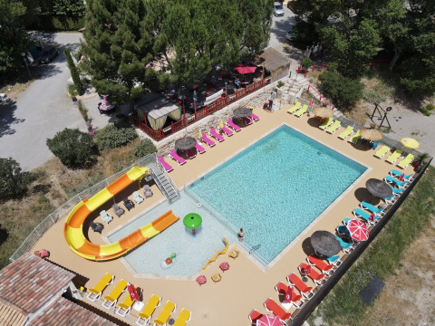 Vista aerea della piscina, scivolo d’acqua e lettini colorati al Flower Camping La Rivière in Provenza, Francia.